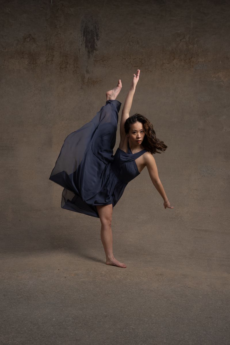 Dancer performing high kick in navy dress