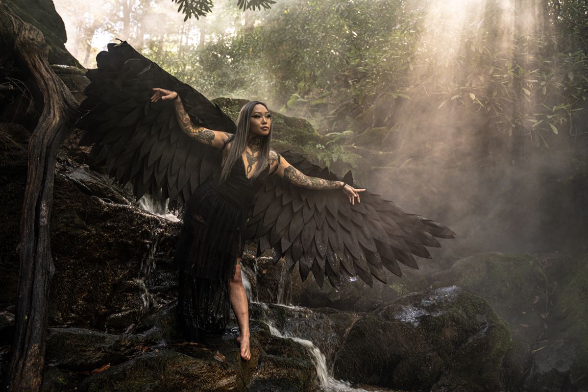 Portrait with dark angel wings at waterfall